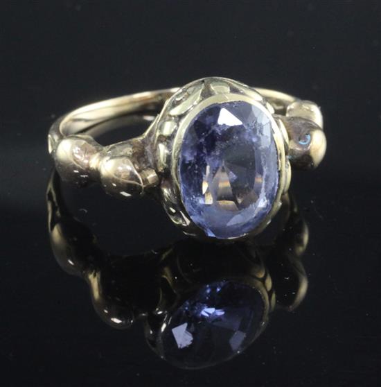 A yellow metal ring set oval sapphire in scrolled mount between seated lion shoulders, size T.